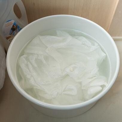 写真：洗い桶に張った洗剤液にシャツを浸けているところ