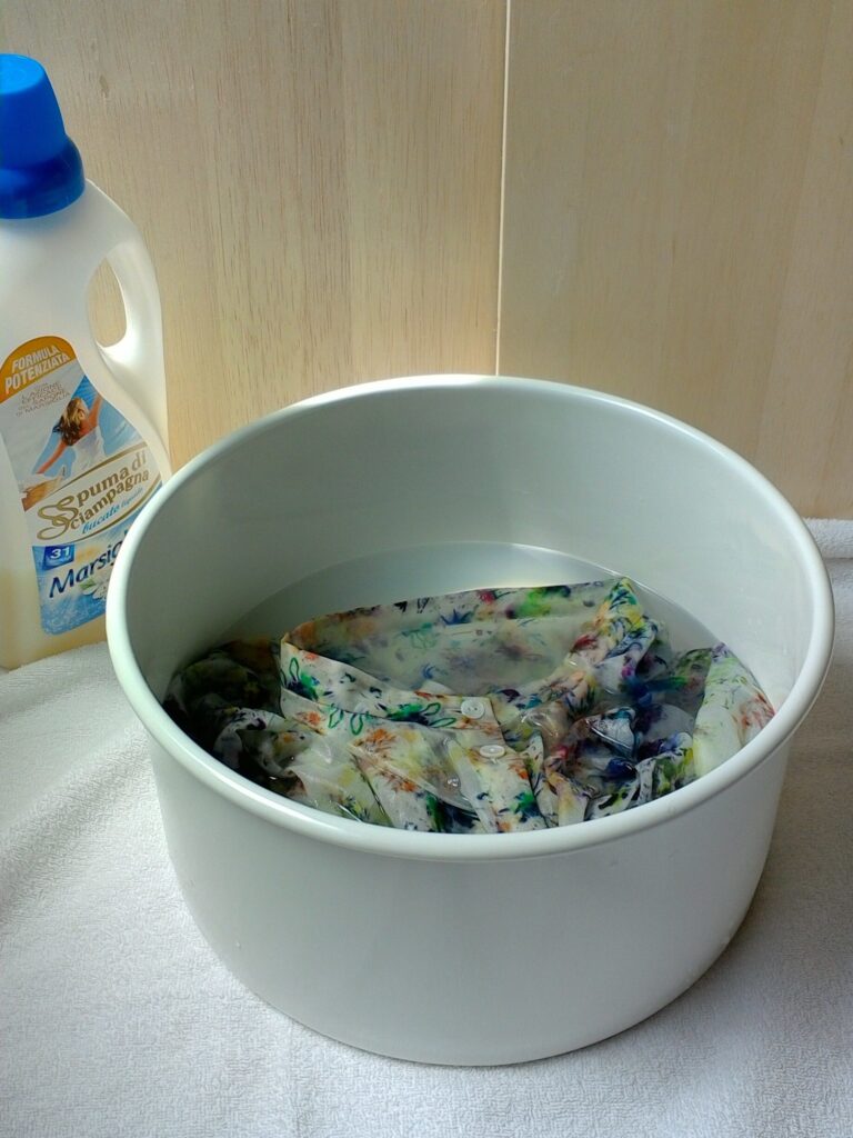 写真：洗い桶の洗剤液にシャツを浸しているところ